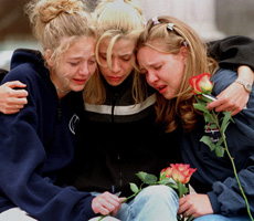 Three girls weep at a memorial